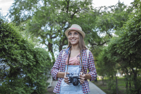 Lächelnde junge Frau mit einer Kamera in einem Park, lizenzfreies Stockfoto