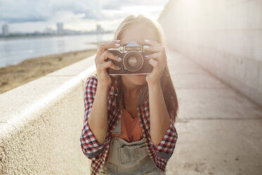 Junge Frau, die ein Foto mit einer Kamera am Flussufer macht - VPIF00159