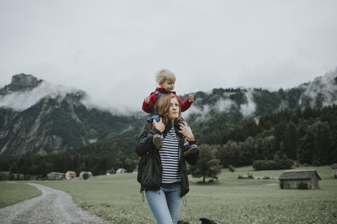 Österreich, Vorarlberg, Mellau, Mutter trägt Kleinkind auf den Schultern bei einem Ausflug in die Berge, lizenzfreies Stockfoto