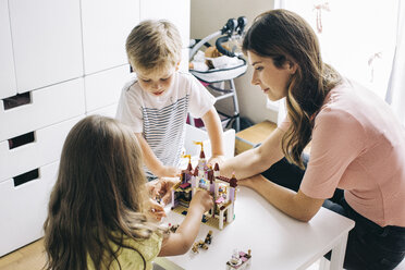Mutter mit zwei Kindern baut zu Hause eine Spielzeugburg auf - JUBF00252