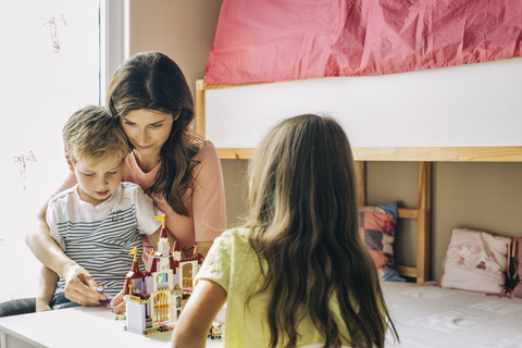 Mutter mit zwei Kindern baut zu Hause eine Spielzeugburg auf, lizenzfreies Stockfoto