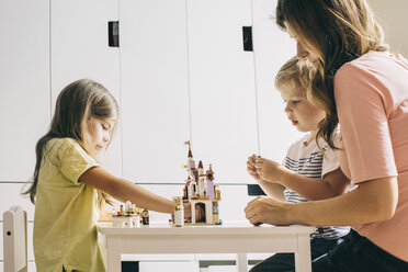 Mother with two children building up toy castle at home - JUBF00255