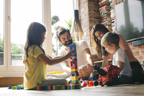 Familie spielt mit Bauklötzen auf dem Boden, lizenzfreies Stockfoto