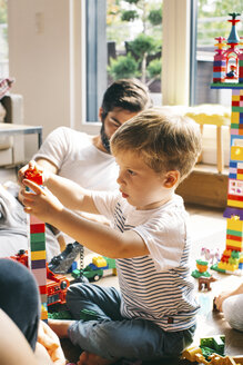 Boy with his family stacking building blocks on the floor - JUBF00260