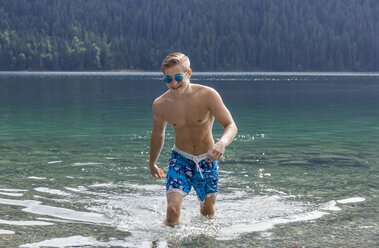 Deutschland, Bayern, Eibsee, junger Mann kommt aus dem Wasser - TCF05447