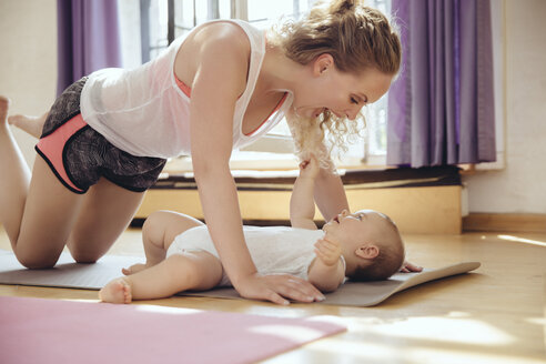 Mutter spielt mit ihrem Baby auf der Yogamatte, während sie trainiert - MFF04006