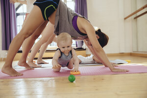 Zwei Mütter trainieren auf Yogamatten, während ihre Babys um sie herum spielen - MFF04008