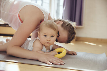 Mother kissing her baby while working out on a yoga mat - MFF04009