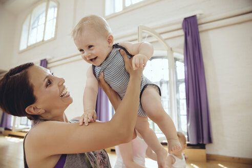 Glückliche Mutter hebt ihr Baby in einem Übungsraum hoch - MFF04013
