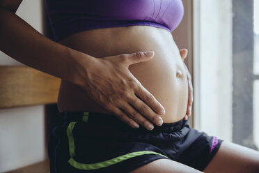 Sportliche schwangere Frau hält ihren Bauch - MFF04029