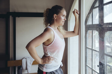 Woman standing in locker room looking out of window - MFF04030