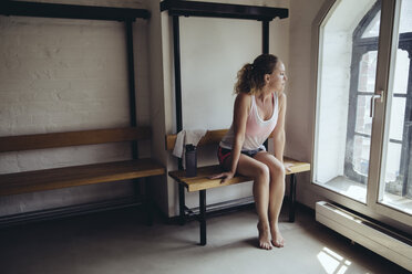 Frau sitzt im Umkleideraum und schaut aus dem Fenster - MFF04035