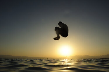 Man jumping into the sea at sunset - ECPF00136