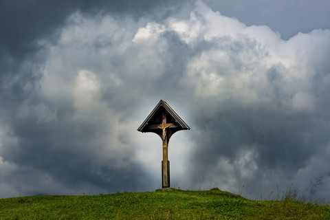 Germany, Bavaria, Allgaeu, Allgaeu Alps, wayside cross with Jesus figurine in front of dramatic sky stock photo