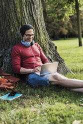 Mann benutzt Laptop im Park - UUF11748