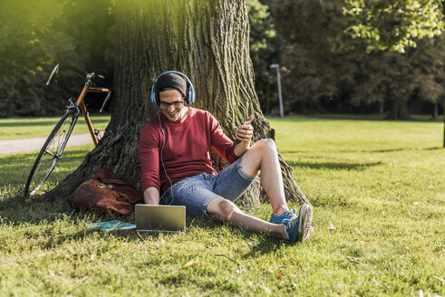 Mann benutzt Laptop im Park - UUF11752