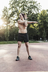 Man doing stretching exercises on sports field - UUF11766