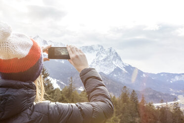 Deutschland, Bayern, Zugspitze, Rückenansicht einer Frau beim Fotografieren mit Smartphone - MMAF00145