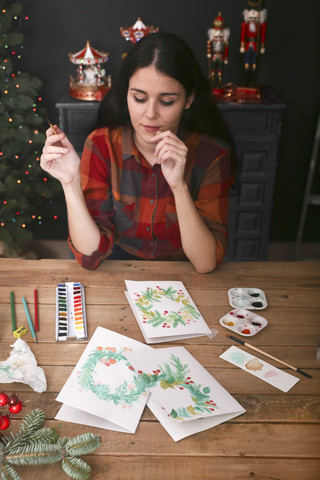 Young woman painting Christmas card with water colors stock photo