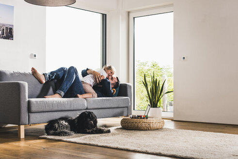 Vater kuschelt mit seiner Tochter auf der Couch - UUF11781