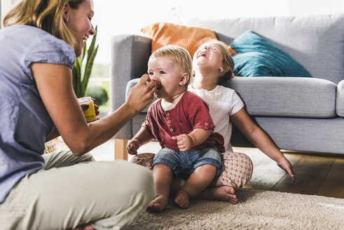 Mutter füttert Kinder im Wohnzimmer - UUF11793