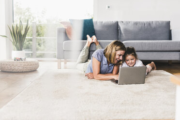 Mother and daughter using laptop, lying on carpet - UUF11798