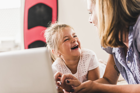 Mutter und Tochter amüsieren sich mit einem Laptop, lizenzfreies Stockfoto