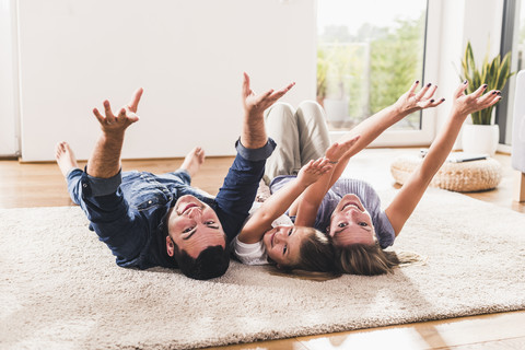 Glückliche Familie, die mit erhobenen Armen auf dem Karpfen liegt, lizenzfreies Stockfoto