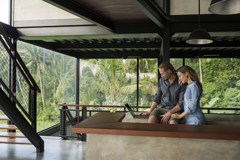 Smiling couple with laptop in modern minimalist kitchen in contemporary design house stock photo