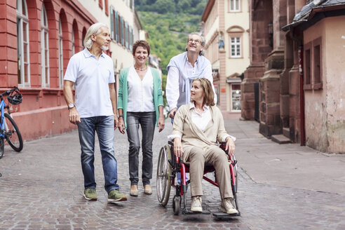 Germany, Heidelberg, senior friends with woman in wheelchair on city trip - PNPF00003