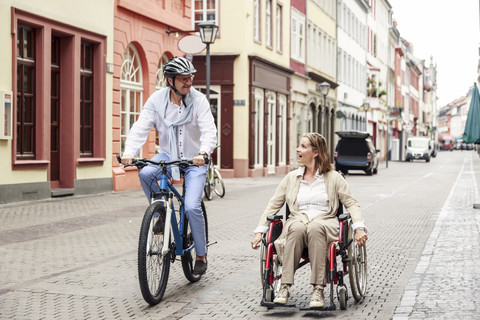 Germany, Heidelberg, woman in wheelchair and man on bicycle in the city stock photo