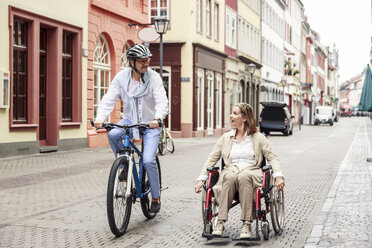 Deutschland, Heidelberg, Frau im Rollstuhl und Mann auf Fahrrad in der Stadt - PNPF00004