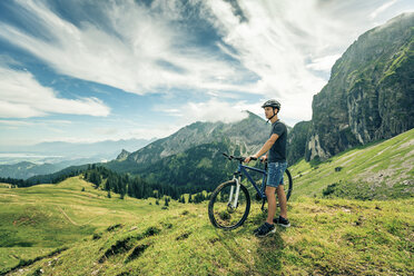 Germany, Bavaria, Pfronten, young man with mountain bike on alpine meadow near Aggenstein - PNPF00020