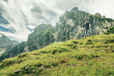 Germany, Bavaria, Pfronten, young man with mountain bike on alpine meadow near Aggenstein - PNPF00021