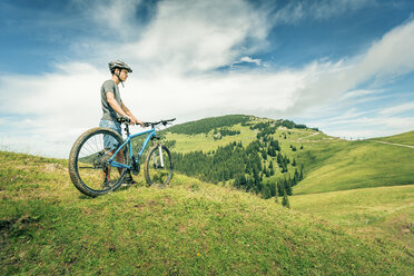 Germany, Bavaria, Pfronten, young man with mountain bike on alpine meadow near Aggenstein - PNPF00022