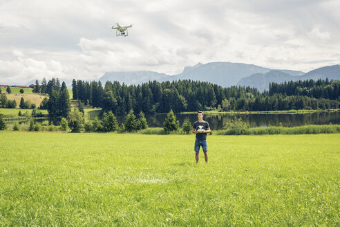 Deutschland, Bayern, Pfronten, junger Mann fliegt seine Drohne am Seeufer - PNPF00034