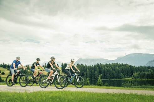 Germany, Bavaria, Pfronten, family riding mountain bikes at ladeside - PNPF00035