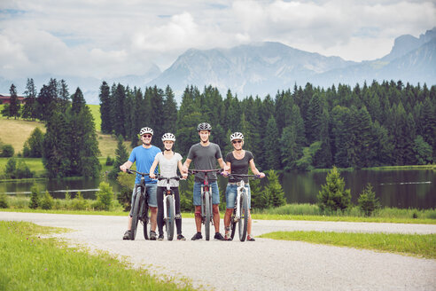 Deutschland, Bayern, Pfronten, Porträt einer glücklichen Familie mit Mountainbikes am Seeufer - PNPF00040