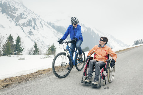 Österreich, Damuels, älteres Ehepaar mit Fahrrad und Rollstuhl genießt einen Wintertag, lizenzfreies Stockfoto