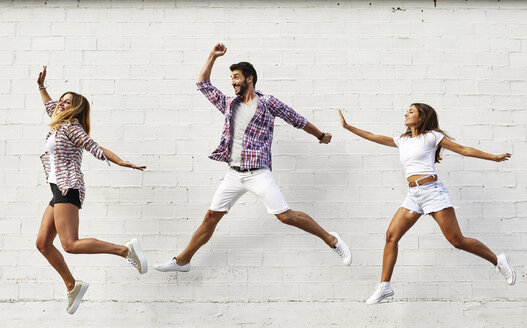Drei Freunde springen in der Luft vor einer weißen Wand - JRFF01449