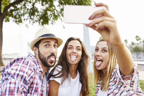 Drei Freunde machen ein Selfie und strecken ihre Zungen heraus, lizenzfreies Stockfoto