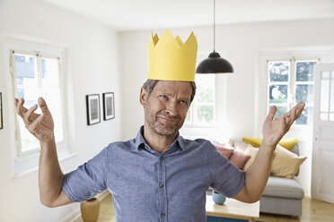 Mature man at home wearing paper crown, looking helpless - PDF01291