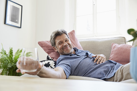 Mann entspannt sich zu Hause und trinkt Wasser, lizenzfreies Stockfoto