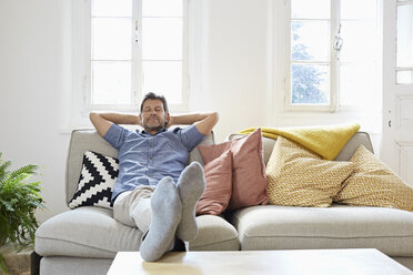 Man sitting on couch at home, relaxing - PDF01306