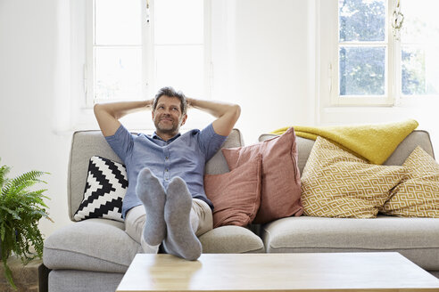 Mann sitzt zu Hause auf der Couch und entspannt sich - PDF01308