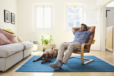Mann entspannt sich zu Hause mit seinem Hund an seiner Seite - PDF01325