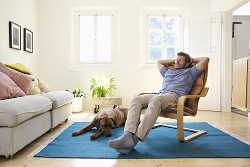 Man relaxing at home with his dog by his side - PDF01325