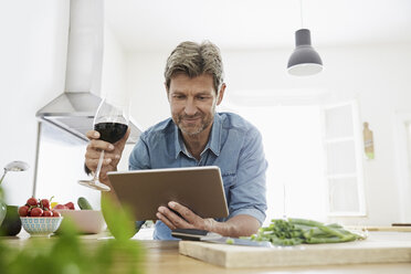Mature man in his kitchen reading recipe on his digital tablet - PDF01346