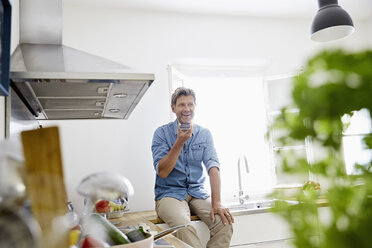 Älterer Mann in seiner Küche singt Smartphone - PDF01352