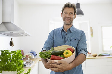 Älterer Mann steht in der Küche und hält eine Schüssel mit Gemüse - PDF01353
